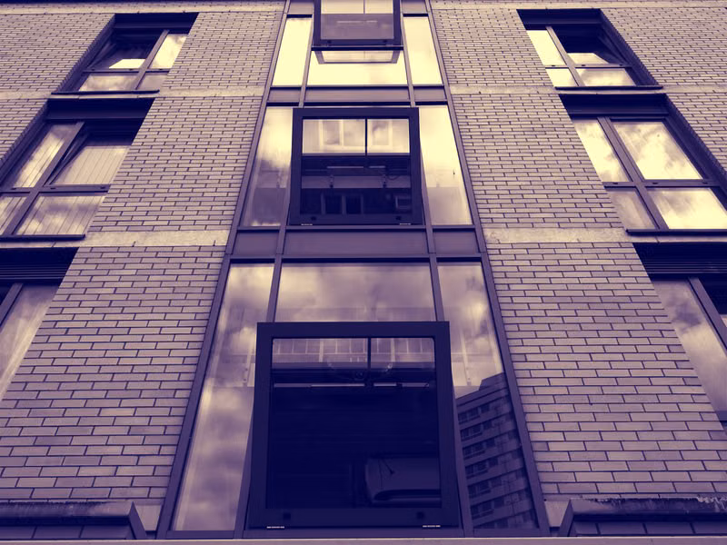 Low-angle view of a modern urban building facade with reflective glass windows