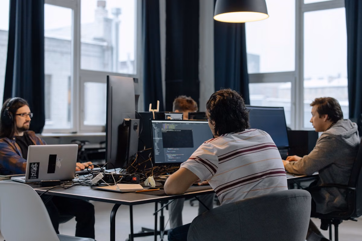 Team of developers collaborating around laptops in a modern tech office