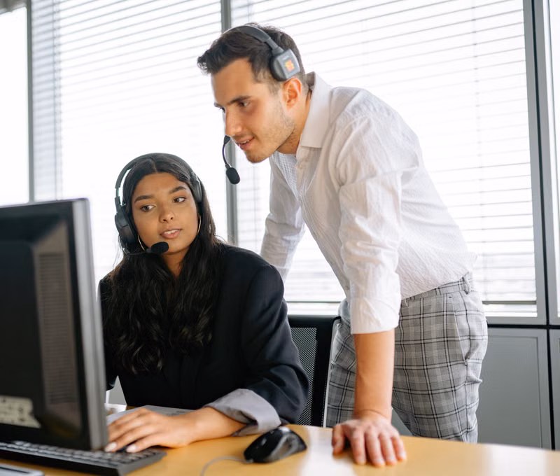 Two customer support agents working together in an office setting